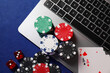 © New Africa - Poker chips, laptop, playing cards and dices on blue table, flat lay. Online game