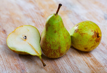 Whole and cut in half ripe green pears on wooden background ..