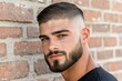 © Thanyarat - A man with a well-groomed beard and a stylish haircut, posing confidently against a brick wall with a casual expression