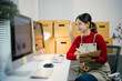© Parichat - Asian sme business owner woman is working in her home office, checking customer orders on a computer and taking notes