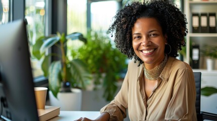 Poster - A woman with curly hair is sitting at a desk with a computer and smiling