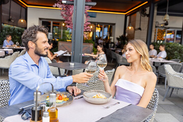 Happy couple toasts in a restaurant with wine