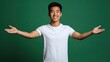 © Pricha.RT - A cheerful Asian American man with open arms and a big smile, posing against a green studio background. His body language exudes warmth and positivity.
