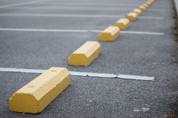 Close up of yellow wheel stopper paver stones at outdoor car park.