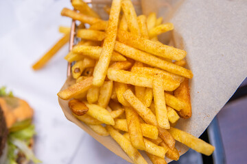 Closeup of a serving of of crispy golden French fries on a restaurant table. A perfect snack or side dish for any fast food meal. Dining out. Fried potato texture. Copy space