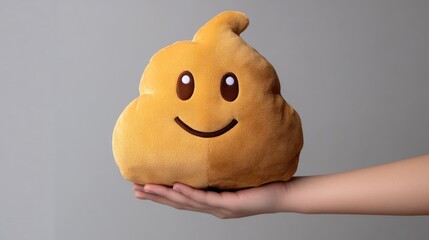 A hand holding a plush toy shaped like a smiling poop emoji.