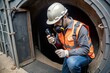 © Gallery BD - A construction worker holds a gas leak detector device while conducting safety gas testing of the atmosphere at the main entry and exit of a confined space door before starting work at a construction