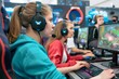 © Svetlana - A fashionable young woman focuses intently on her computer screen, participating in an online PvP tournament, while communicating with her team via a headset.