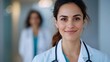 © Jane_S - Young female doctor in a hospital setting, wearing a white coat and pink stethoscope, representing professionalism and care in healthcare.