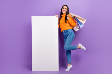 Wall Mural - Full length photo of cheerful pretty lady wear trendy clothes demonstrate screen display empty space isolated on purple color background