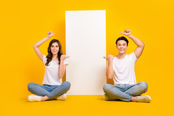 Poster - Full length photo of charming funny couple wear white t-shirts pointing thumbs gadget empty space isolated yellow color background