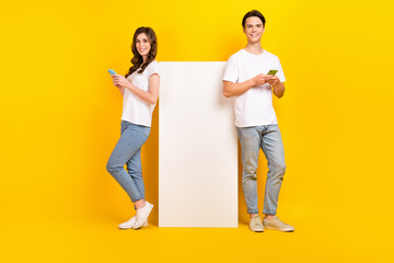 Poster - Full length photo of positive cute couple wear white t-shirts chatting telegram facebook empty space isolated yellow color background