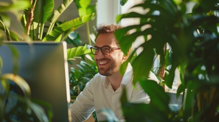 Poster - A man is sitting in front of a computer monitor with a smile on his face