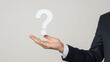 © pattozher - The Question Mark:  A businessman holds a large white question mark, symbolizing uncertainty, doubt, and the need for answers in a professional setting.