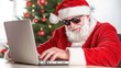 © pvl0707 - A cheerful man in a Santa costume joyfully types on a laptop while hiding behind a Christmas tree in a bright room