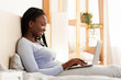 © Prostock-studio - Smiling African American Lady Working On Laptop On Weekend Sitting In Bed At Home. Freelance Lifestyle. Panorama, Selective Focus