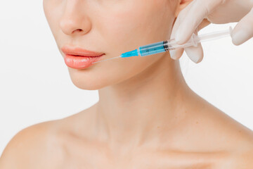 A young beautiful woman receiving a Botox injection against a white studio background. The close-up highlights her serene expression, emphasizing self-care and the aesthetic procedure.