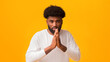 © Prostock-studio - Serious black man holding his hands in praying gesture over orange background