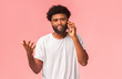 © Prostock-studio - Emotional african american guy talking on mobile phone and gesturing, pink background, free space