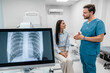 © InsideCreativeHouse - Caucasian young male medic doctor specialist radiologist in blue uniform explaining diagnosis on lung x-ray fluorography to female patient during medical appointment in hospital.