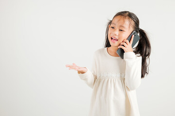 Happy Asian portrait cute young kid girl smiling excited talking smart mobile phone studio shot isolated on white background, Thai kindergarten child calling gesture on smartphone