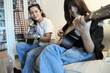 © kimberrywood - The Asian single mother teaching daughter to play guitar in the living room.