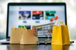 © typepng - The concept of online shopping and delivery is illustrated by product package boxes in a cart, a shopping bag, and a laptop computer with a blurry online store shop displayed on screen