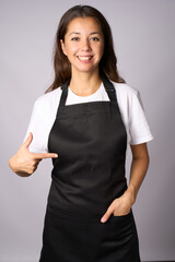 Young woman wearing black apron pointing on apron with finger