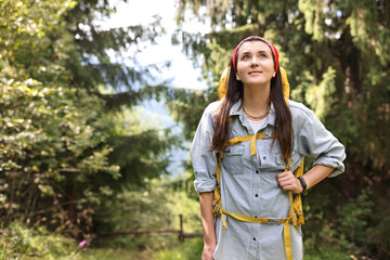 Wall Mural - Young hiker with backpack looking at something in forest, low angle view