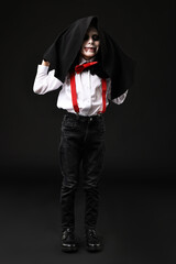 Wall Mural - Funny boy dressed like vampire for Halloween celebration on black background