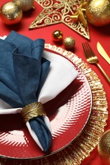 Wall Mural - Christmas place setting with festive decor on red table, closeup