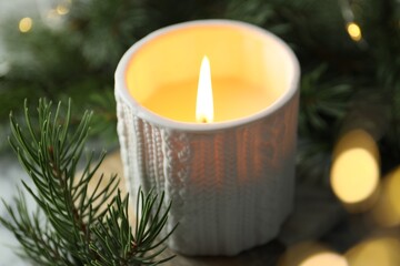 Sticker - Burning candle, fir tree branches on table against blurred lights, closeup