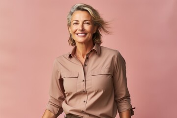 Sticker - Portrait of a jovial woman in her 50s sporting a breathable hiking shirt isolated in soft brown background