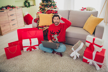 Canvas Print - Full body portrait of nice young man eshopping laptop sweater christmas holiday time flat indoors