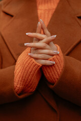 Poster - Close up fashion details of brown coat and knitted orange sweater on female figure, warm autumn seasonal clothing