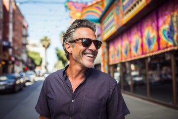 Wall Mural - Portrait of a smiling man in his 50s wearing a trendy sunglasses in front of vibrant market street background