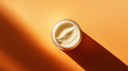 Poster - A jar of cream with a swirl of product visible from above, sitting on an orange background with a shadow