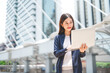 © dodotone - Business freelance adult asian woman using laptop standing at outdoor on day