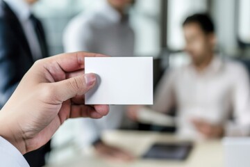 A man holds a white business card in front of a group of people