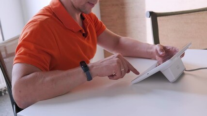 Canvas Print - a man is sitting at a table and using a tablet to work.