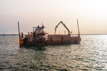 A barge on the sea moored with a crane and worksite equipment