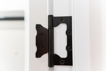 Sticker - This image showcases a detailed closeup view of a black door hinge that is affixed to a white door, highlighting the contrast between the colors and materials used in this fixture