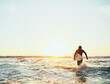 © StarDweller/peopleimages.com - Running, surfer and man with surfboard at beach for water sport, adventure and tropical vacation. Back, tourist and person for surfing at ocean with fitness, mockup and activity for hobby and sunset