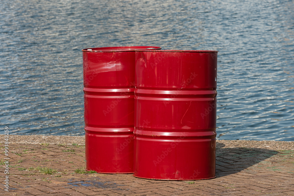 two red steel oil barrels stand on the quay of the port