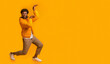 © Prostock-studio - Funny black guy fooling, dancing in egypt style, wearing glasses and winter jacket on orange studio background