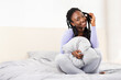 © Prostock-studio - Smiling Black Lady Holding Blanket Playing With Braided Hair Sitting And Posing In Bed At Home In Morning. Selective Focus