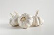 © Fotograf - Three garlic heads sit on a clean white surface