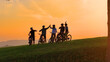 © helivideo - SILHOUETTE: Golden sunset and a group of mountain bikers celebrating on top of the hill after joyful uphill ride. Beautiful autumn day for cycling and exploring the scenic countryside with friends.