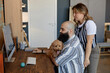 © Seventyfour - Two coworkers collaborating on project at home office with pet dog beside them Person sitting at desk working on computer while another stands providing input