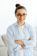© Kateryna - Vertical portrait of a confident, intelligent, gorgeous indian or arabian woman with glasses, successful manager, advisor, digital seo, standing indoors with arms crossed, looking at camera, smiling